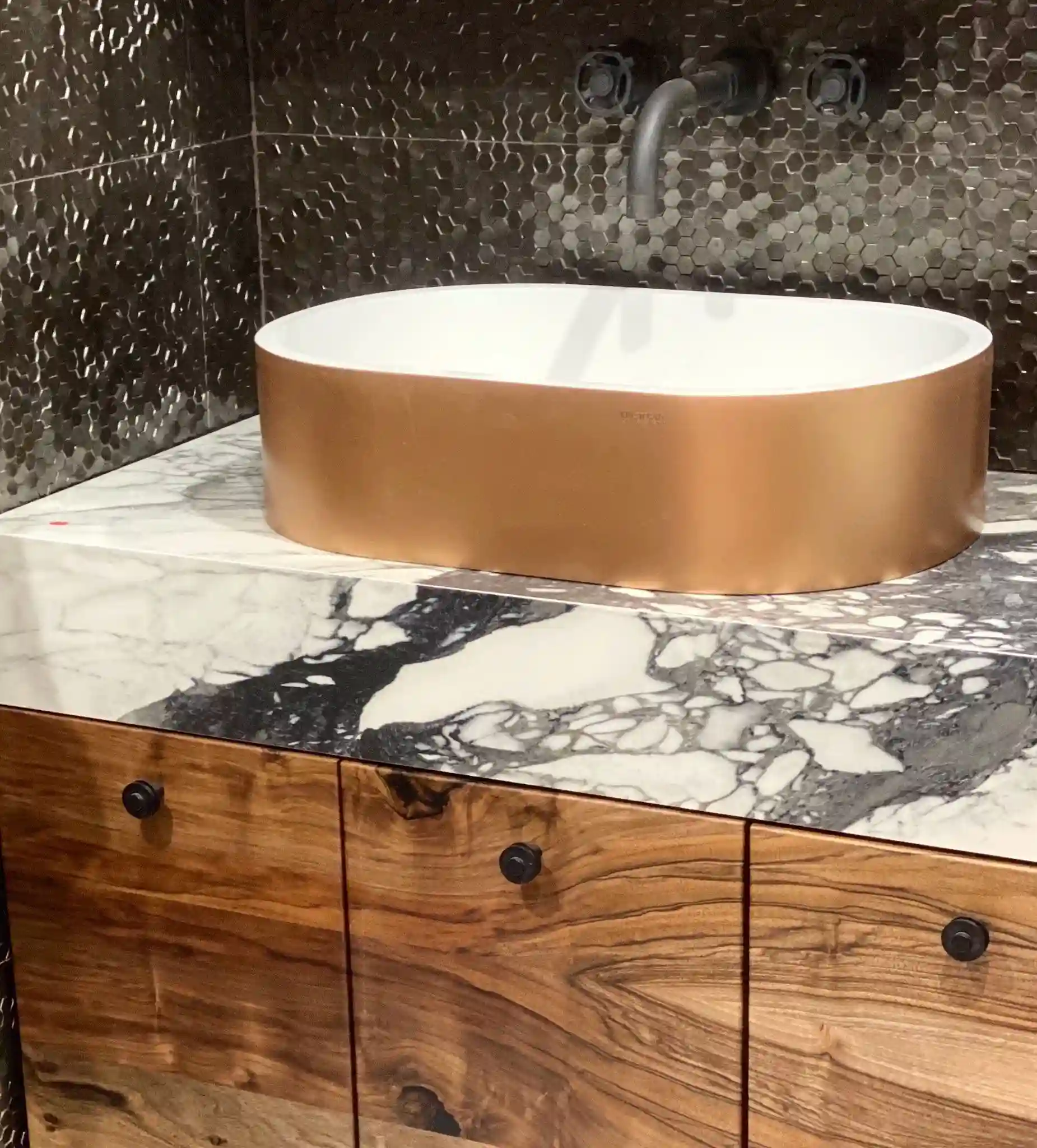 Round copper vessel sink on a dramatically veined black and white stone vanity