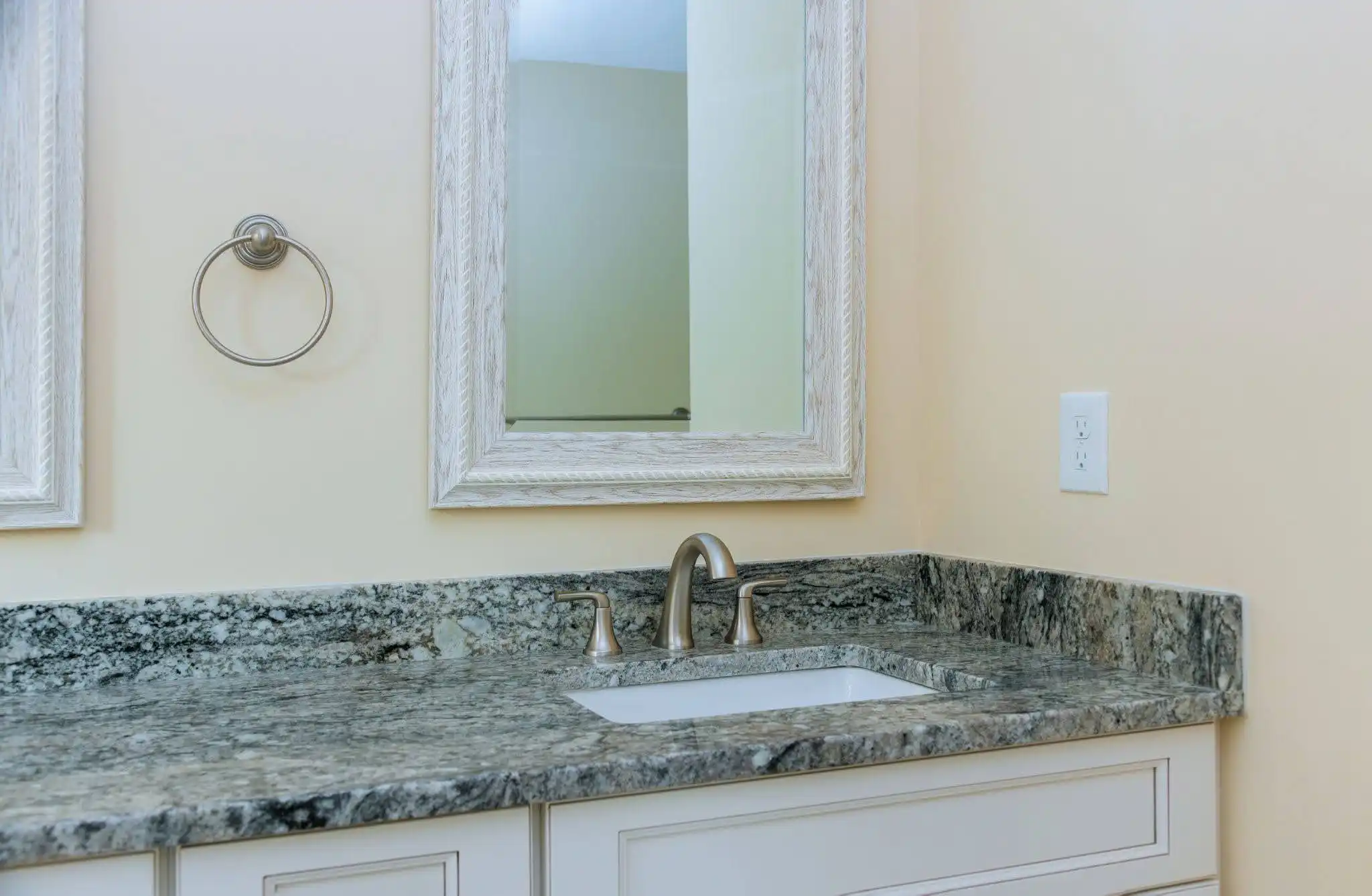 White bathroom vanity with a dark gray natural stone countertop and backsplash
