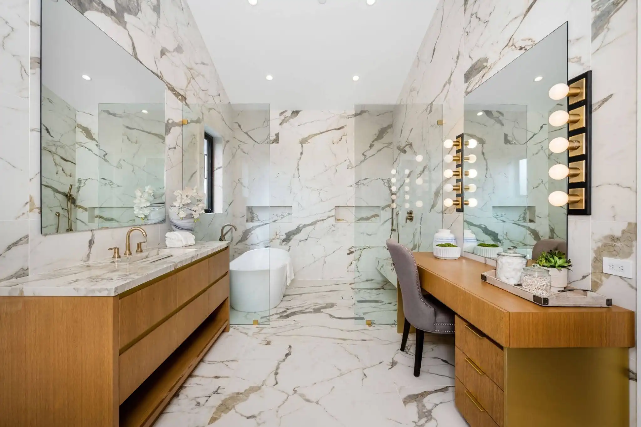 Warm natural stone bathroom with wood vanities and floor-to-ceiling veining
